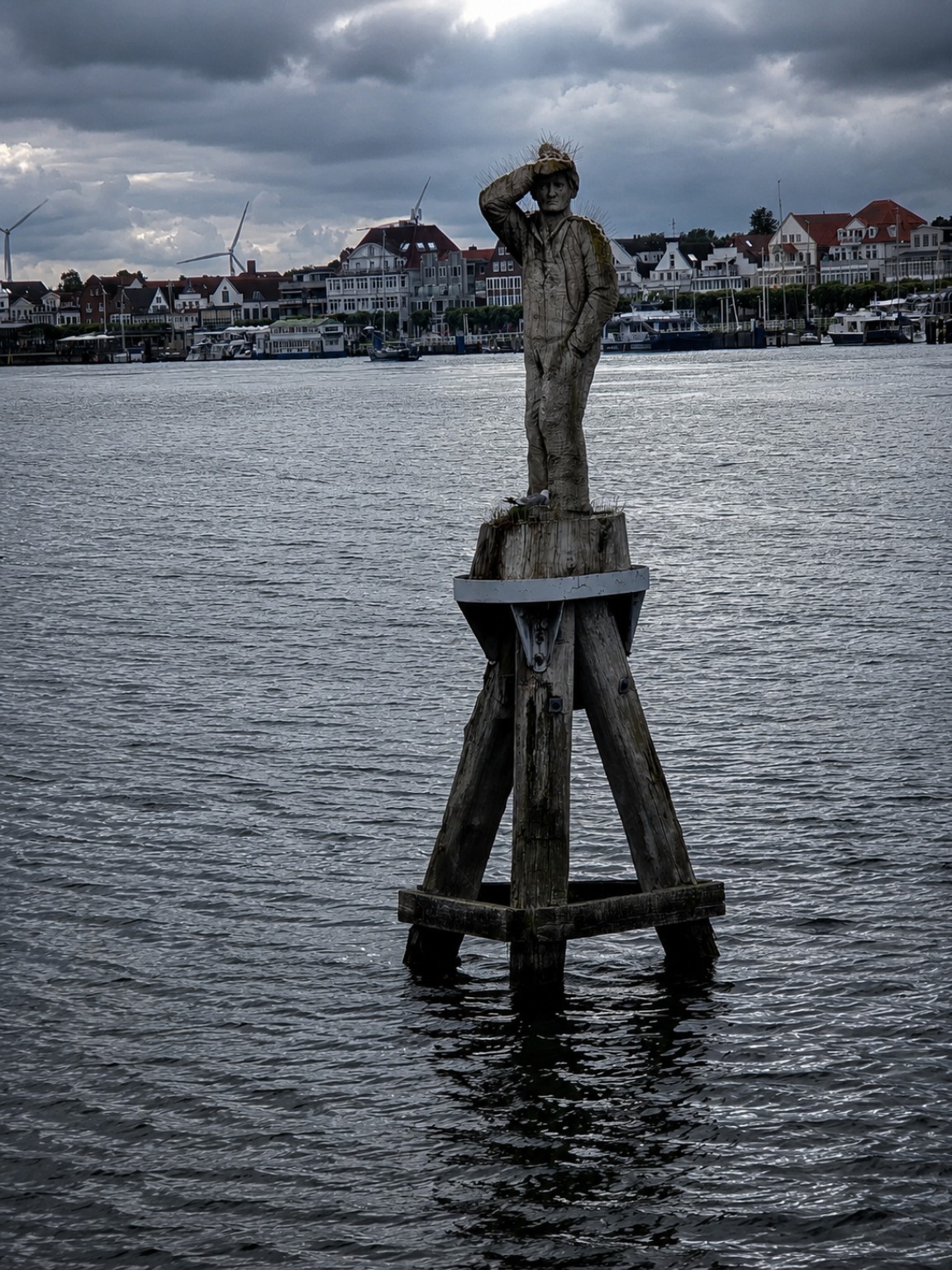 Wooden lookout figure standing above the water beneath dramatic clouds