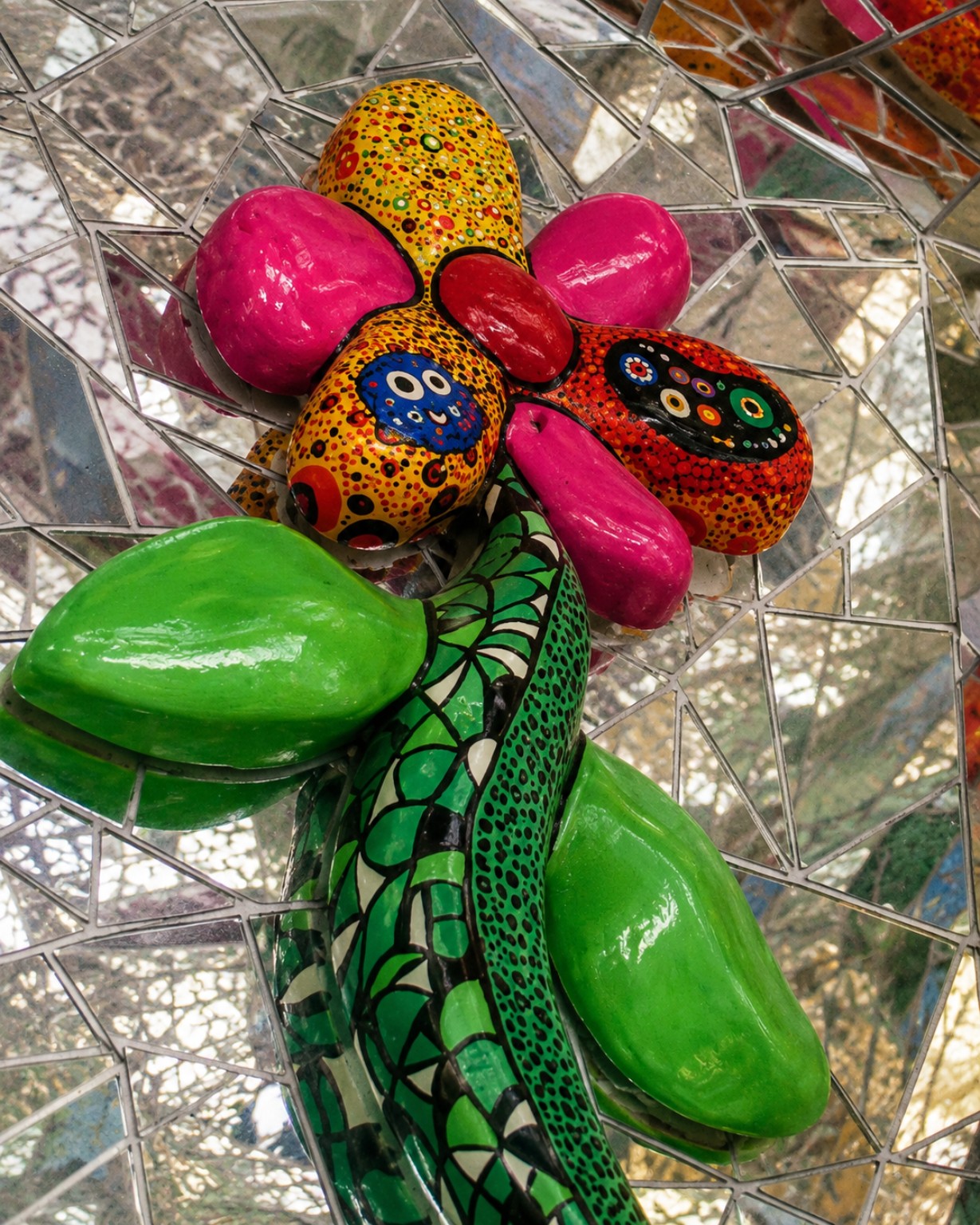Bright mosaic flower sculpture reflected in mirrored fragments